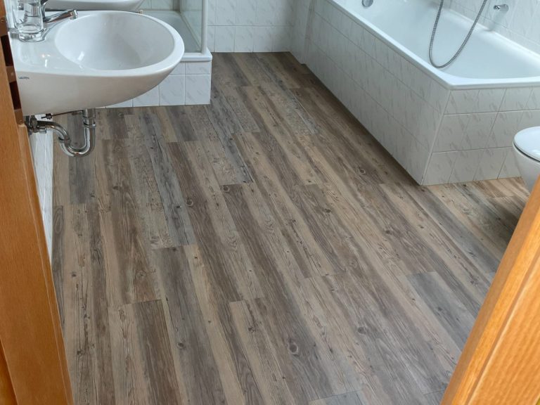 Vinylboden Helles Badezimmer mit Vinylboden, Badewanne, Waschbecken und Dusche.