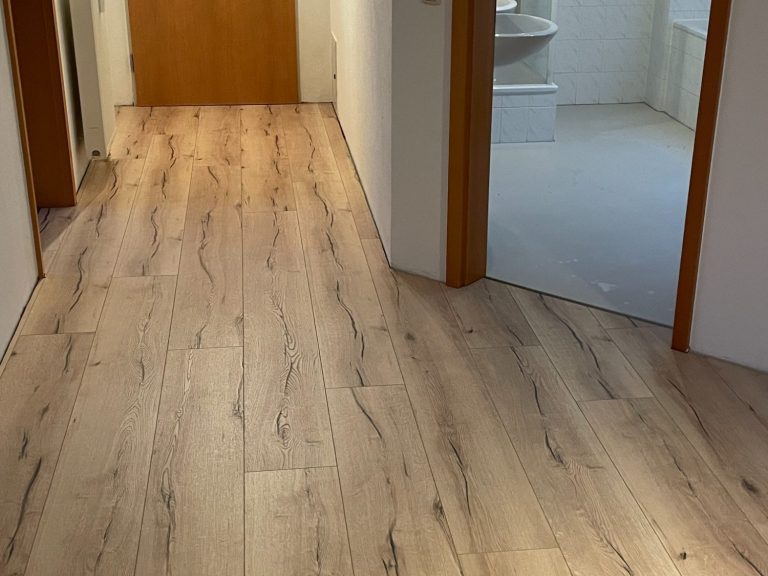 Laminatböden Langer Flur mit hellen Laminatböden und Zimmern auf beiden Seiten.