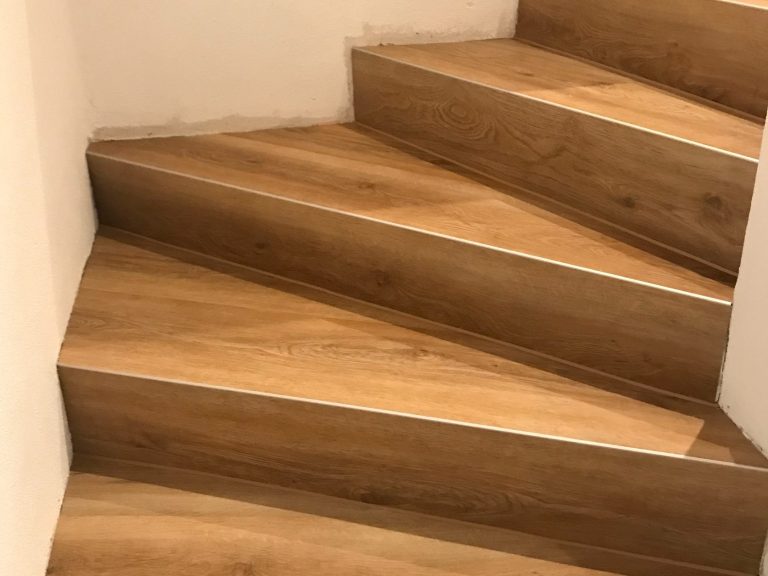Vinyl-Treppenstufen Treppe mit hellbraunen Vinyl-Treppenstufen und grauem Wandanstrich.