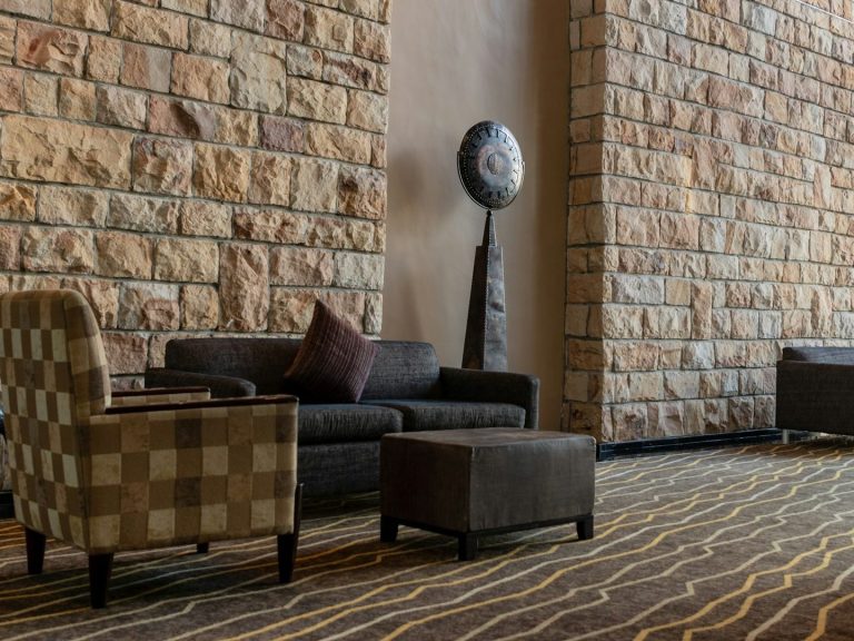 Teppichböden Wohlfühlbereich mit gestreiftem Teppich, bequemen Möbeln und einer Steinwand.