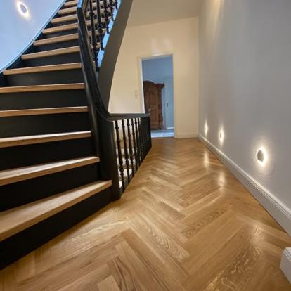 Flur und Treppe Holztreppe mit schwarzem Geländer, hölzernen Böden und sanfter Beleuchtung im Flur.